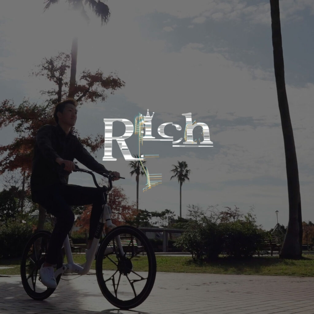 メンテナンスフリー自転車Richのプロモーションビデオサムネイル　緑道を軽快に自転車で走る男性の写真