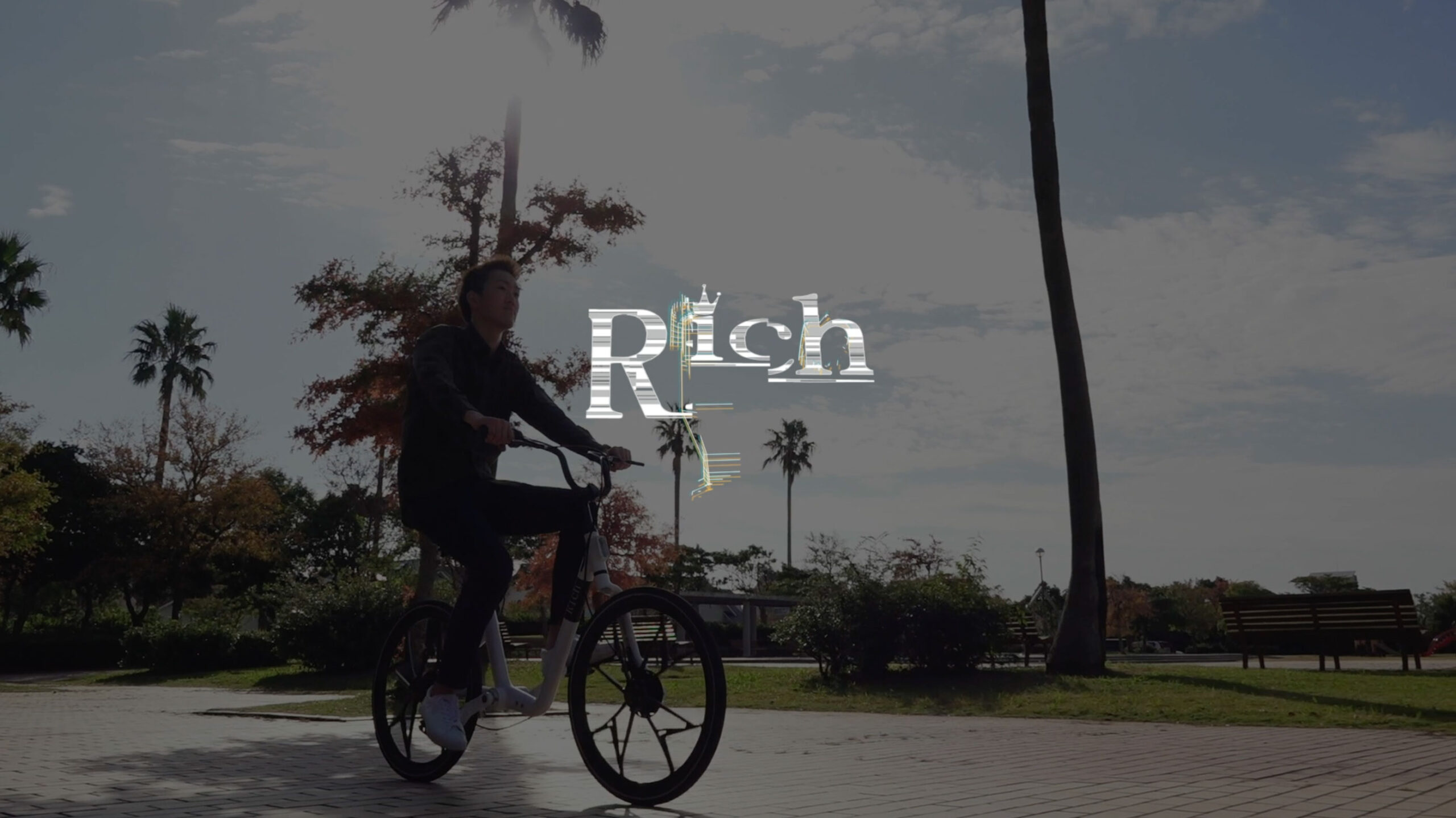 メンテナンスフリー自転車Richのプロモーションビデオサムネイル　緑道を軽快に自転車で走る男性の写真