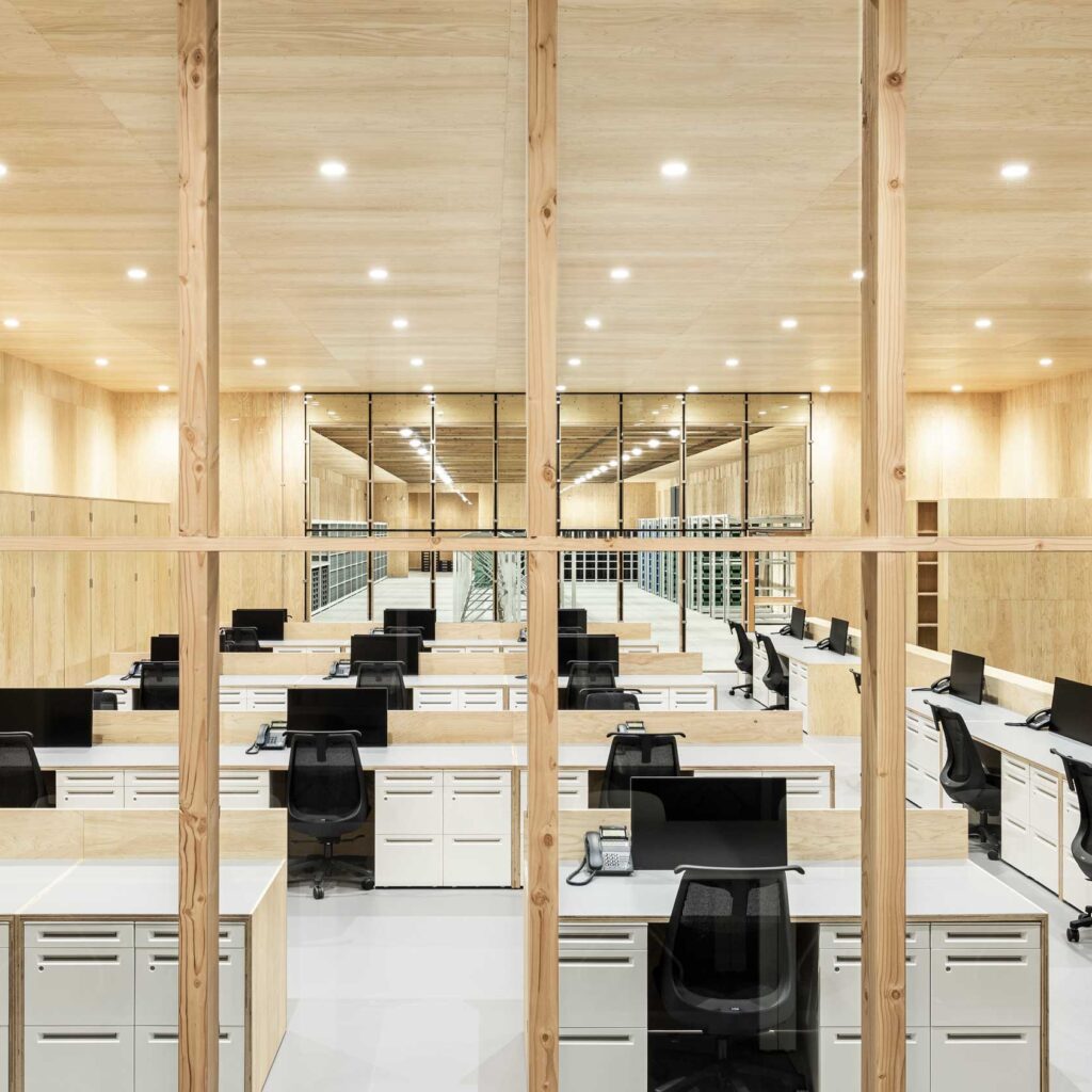株式会社三井の事務所風景　美しい木目の壁と天井に囲まれた広い空間にスタイリッシュなデスクとワークチェアが整列した写真